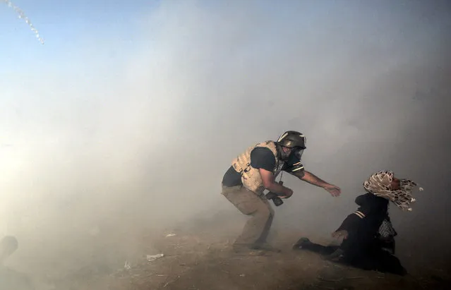 A photojournalist trying to help a female protester after Israelis fire tear-gas during clashes near the border with Israel in the east of Gaza Strip, 15 May 2018.  At least 62 Palestinian protesters were killed and more than 2,500 others were injured at the Gaza-Israeli border during clashes against the US embassy move to Jerusalem as well as marking the Nakba Day. Palestinians are marking the Nakba Day, or the day of the disaster, when more than 700 thousand Palestinians were forcefully expelled from their villages during the war that led to the creation of the state of Israel on 15 May 1948. Protesters call for the right of Palestinians to return to their homeland. (Photo by Mohammed Saber/EPA/EFE)