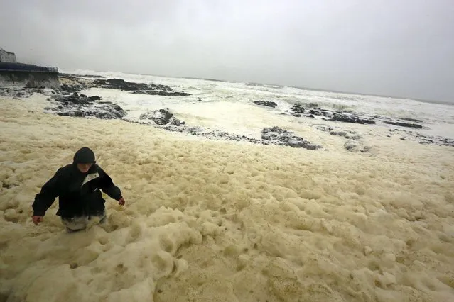 A man walks through sea foam created by storms, in the town of Portstewart on the Irish Coast January 9, 2015. (Photo by Cathal McNaughton/Reuters)