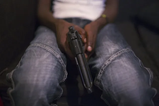 A young man, who says he is part of a local criminal gang, poses for a picture holding a gun in the neighbourhood of Korogcho in Nairobi, Kenya, March 19, 2015. (Photo by Siegfried Modola/Reuters)