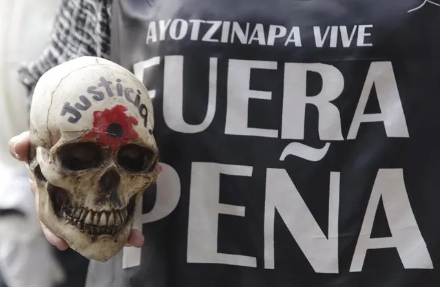 A woman holds up a skull as she takes part in a march to mark the 14-month anniversary of the disappearance of the students from Ayotzinapa College Raul Isidro Burgos, in Mexico City, Mexico November 26, 2015. Hundreds of activists marched on Thursday in Mexico City to demand justice for 43 students who disappeared over a year ago in the southwestern state of Guerrero. (Photo by Daniel Becerril/Reuters)