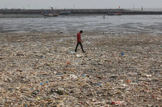 A man walks on a garbage-strewn beach in Mumbai, India, May 28, 2018. (Photo by Francis Mascarenhas/Reuters)