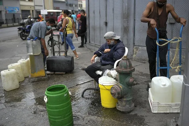 Residents tap into a fire hydrant to fill their containers with water in the San Juan neighborhood of Caracas, Venezuela, Tuesday, January 19, 2021, amid the new coronavirus pandemic. Venezuela's economic crisis has sent millions fleeing and those left behind lacking basic goods, including gasoline, in a country with one of the world's largest proven oil reserves. (Photo by Matias Delacroix/AP Photo)