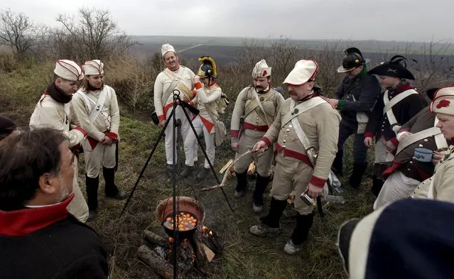 Historical re-enactment enthusiasts dressed as soldiers cook near the southern Moravian village of Herspice December 4, 2015. (Photo by David W. Cerny/Reuters)