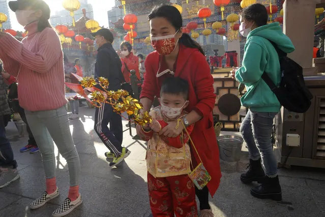 Worshippers wearing face masks to protect against the spread of the coronavirus, pray at the Wong Tai Sin Temple, in Hong Kong, Friday, February 12, 2021, to celebrate the Lunar New Year which marks the Year of the Ox in the Chinese zodiac. (Photo by Kin Cheung/AP Photo)