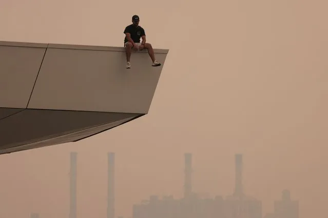 A person sits on a lookout in Long Island City in Queens, as haze and smoke caused by wildfires in Canada blanket New York City, New York, U.S., June 7, 2023. (Photo by Andrew Kelly/Reuters)