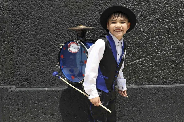 Dressed as a Chilean “Chinchinero” Simon Saavedra, 8, poses for a photo before a march during the First Festival of Organ Grinders in Mexico City, Sunday, May 21, 2023. A “Chinchinero” is an urban street performer in Chile, usually a man or young boy, who plays a bass drum-type percussion instrument with long drumsticks strapped to his back which also involves a rope with a noose tied around the performer's foot to play the cymbals which also form part of this improvised instrument. (Photo by Ginnette Riquelme/AP Photo)