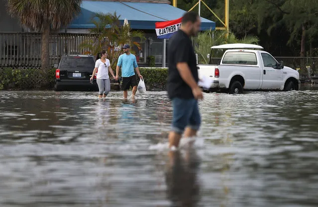 Yaneisy Duenas (left) and Ferando Sanudo walk through the flooded parking lot to their boat at the Haulover Marine Center on November 14, 2016 in North Miami, Fla. The flood waters are caused by the combination of the lunar orbit which causes seasonal high tides, also known as a King tide, and what some scientists believe is rising sea levels due to climate change. (Photo by Joe Raedle/Getty Images)