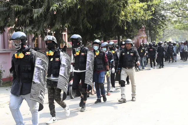 Anti-coup protesters wearing helmet and face mask march during a protest in Mandalay, Myanmar, Saturday, March 6, 2021. (Photo by AP Photo/Stringer)