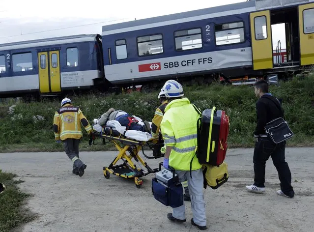 An injured victim is wheeled away at the scene where two Swiss regional trains collided head on near Granges-Pres-Marnand near Payerne in western Switzerland July 29, 2013. The two trains collided in the Swiss canton of Vaud on Monday evening, injuring about 40 people, four seriously, Swiss news agency ATS reported. There was no immediate report of any deaths in the crash. (Photo by Denis Balibouse/Reuters)