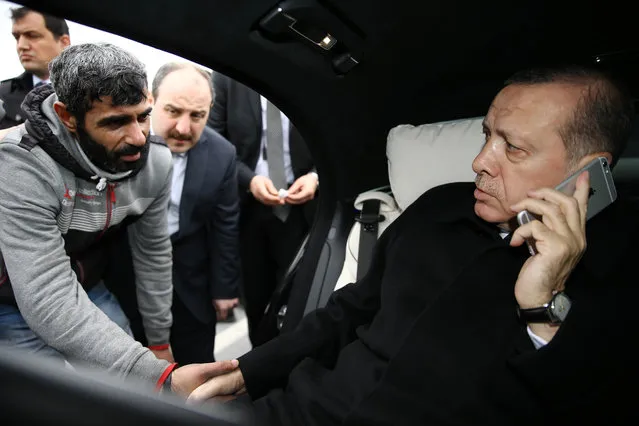 Turkish President Recep Tayyip Erdogan, right, takes Vezir Cakras by hand while speaking on his mobile phone inside his car stationed over the Bosporus Bridge in Istanbul, Friday, December 25, 2015. Erdogan's office says the Turkish president has talked Cakras out of jumping off a bridge to commit suicide. Television footage on Friday showed Erdogan's motorcade stopping over Istanbul's Bosporus Bridge where a man was apparently contemplating jumping off. An official from Erdogan's office told the Associated Press that Vezir Cakras was depressed because of “family issues”. (Photo by Yasin Bulbul/Presidential Press Service Pool via AP Photo)