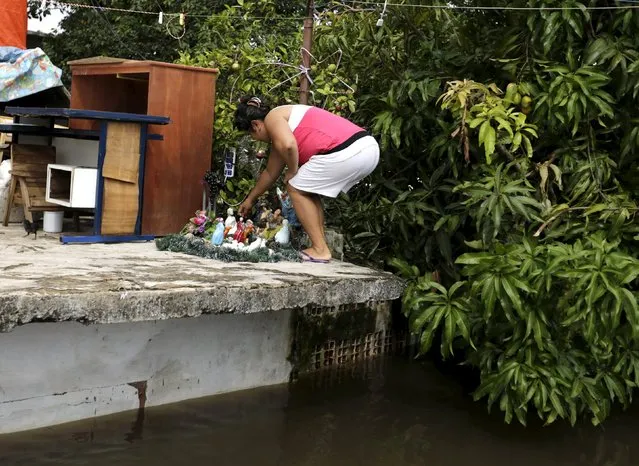 A woman arranges a nativity scene on top of her house above flood waters in Asuncion, December 27, 2015. (Photo by Jorge Adorno/Reuters)