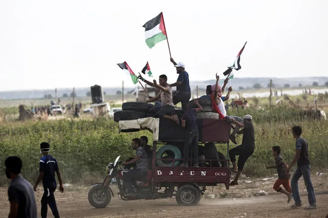 Men wave national flags while riding a motorcycle-taxi, called a Toktok, loaded with tires to be burned during a protest at the Gaza Strip's border with Israel, Friday, August 3, 2018. Gaza's Hamas rulers led several thousand Palestinians in a protest along the frontier with Israel on Friday – a show of presence by Hamas as Egyptian efforts intensify to broker a broad truce between the Islamic militant group and Israel. (Photo by Khalil Hamra/AP Photo)
