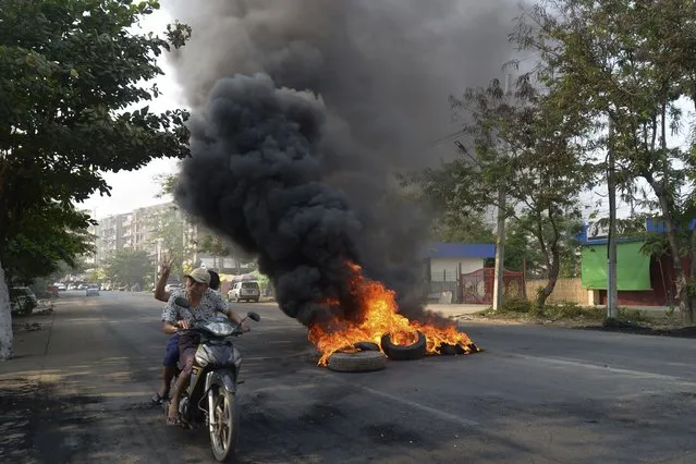 Anti-coup protesters pass burning tires in Yangon, Myanmar on Thursday March 24, 2021. (Photo by AP Photo/Stringer)