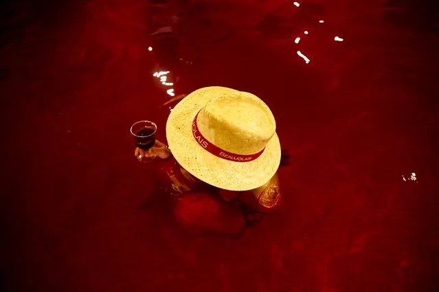 A woman drinks wine in a hot bath with coloured water representing wine at the Hakone Kowaki-en Yunessun spa resort during an event marking Beaujolais Nouveau Day in Hakone west of Tokyo, November 19, 2015. (Photo by Thomas Peter/Reuters)