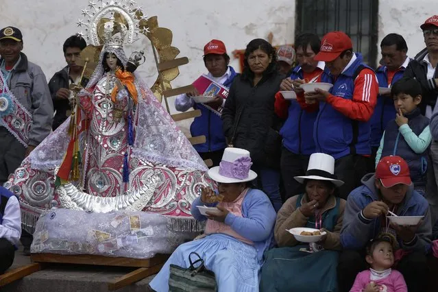 In this Sunday, August 5, 2018 photo, “cargadores” or male carriers and devotees lunch on free bowls of beef and wheat soup during a pause in the religious procession honoring Our Lady of Copacabana, in Cuzco, Peru. It is expected that the organizers provide free food and drink along with a small fee for the dancers and musicians. According to the steward of this year's celebrations, expenditures totaled 9,000 U.S. dollars. (Photo by Martin Mejia/AP Photo)