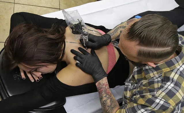 Tattooist Eddy Del Rio, right, applies a tattoo to Alexa Barosky at Anchor Ink Tattoo, Tuesday, February 10, 2015, in Salt Lake City. Lawmakers have decided more discussion is needed on a proposal that would place an outright ban on tattooing minors, even with parental permission. During a Tuesday afternoon hearing, a committee decided to hold on to the proposal from Rep. LaVar Christensen, a Draper Republican. (Photo by Rick Bowmer/AP Photo)