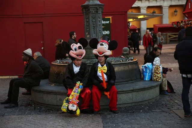 Two street performers dressed in Mickey Mouse costumes take a break at Plaza Mayor square in Madrid, Spain, November 28, 2016. (Photo by Susana Vera/Reuters)