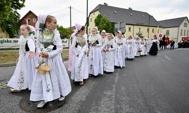Girls dressed in the traditional clothes of Sorbs take part in the annual Corpus Christi procession in Crostwitz, Germany, June 16, 2022. (Photo by Matthias Rietschel/Reuters)