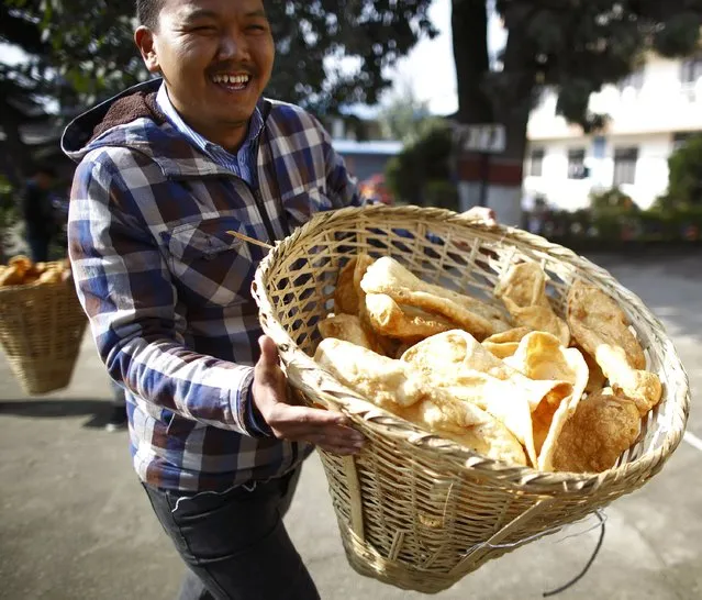 A Tibetan man carries a basked filled with Tibetan food called “khapse”, which he serves to guests during a function organised to mark Losar or the Tibetan New Year at Tibetan Refugee Camp in Lalitpur February 19, 2015. (Photo by Navesh Chitrakar/Reuters)