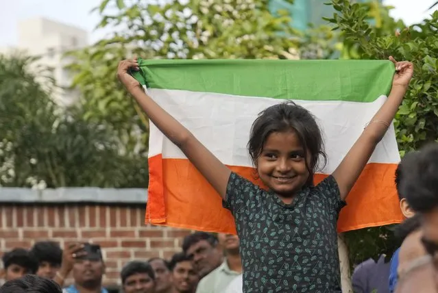 A girl stands with the Indian national flag as she watches a live telecast of the landing og Chandrayaan-3, or “moon craft” in Sanskrit, in Mumbai, India, Wednesday, August 23, 2023. (Photo by Rajanish Kakade/AP Photo)