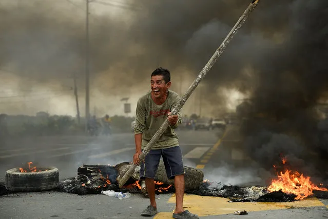 A protester reacts in front of a burning roadblock on a highway to Guayaquil during continuing demonstrations against the government of President Guillermo Lasso due to price increases for fuel, food and other basics, in Limonal, Ecuador on June 22, 2022. (Photo by Vicente Gaibor del Pino/Reuters)