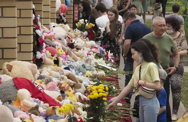 People lay flowers and toys near a school after a shooting on Tuesday in Kazan, Russia, Thursday, May 13, 2021. Russian officials say a gunman attacked a school in the city of Kazan and Russian officials say several people have been killed. Officials said the dead in Tuesday's shooting include students, a teacher and a school worker. Authorities also say over 20 others have been hospitalised with wounds. (Photo by Dmitri Lovetsky/AP Photo)