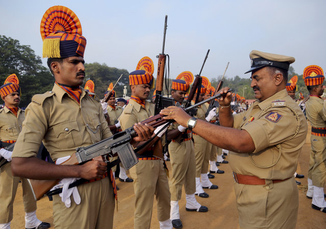 An Indian police officer checks a gun of a policeman to make sure there are no bullets inside it before performing at the Republic Day celebrations in Bangalore, India, Tuesday, January 26, 2016. India celebrated its Republic Day Tuesday, highlighted by a march by different branches of the military as well as a display of arms and missiles. (Photo by Aijaz Rahi/AP Photo)