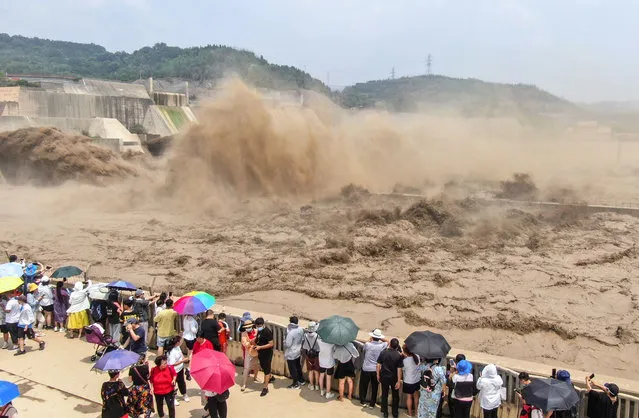 This aerial photo taken on July 5, 2021 shows people watching water being released from the Xiaolangdi Reservoir Dam in Luoyang in China's central Henan province. (Photo by AFP Photo/China Stringer Network)