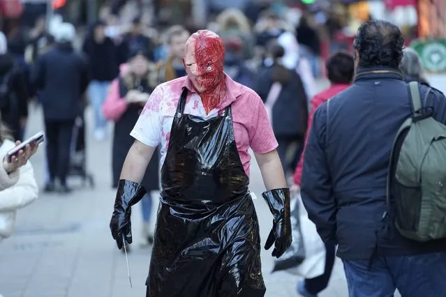 A man dressed up in a costumes walks a shopping street on his way to a Halloween Zombie meeting in Essen, Germany, Tuesday, October 31, 2023. (Photo by Martin Meissner/AP Photo)