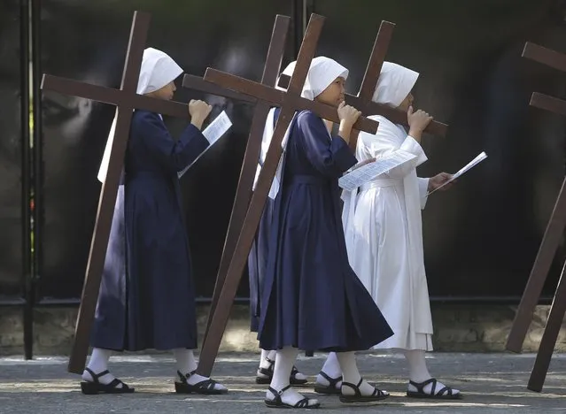 Filipino nuns carry wooden crosses as they make the Stations of the Cross at the Philippine Center of Saint Pio of Pietrelcina on Wednesday, April 1, 2015 in suburban Quezon city, east of Manila, Philippines. Devotees practice different religious rites during the Holy Week in this predominantly Roman Catholic country. (Photo by Aaron Favila/AP Photo)