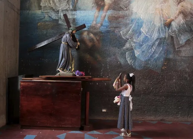 A girl uses her mobile phone to take pictures of a statue of Jesus at the Metropolitan Cathedral in Managua April 7, 2015. (Photo by Oswaldo Rivas/Reuters)