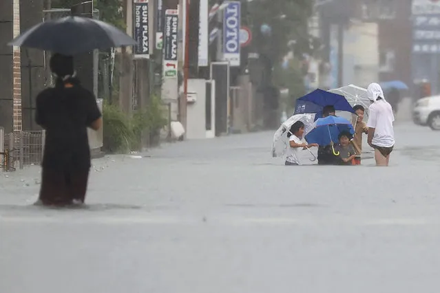 People wade through a road flooded by heavy rain in Kurume, Fukuoka prefecture, western Japan, Saturday, August 14, 2021. (Photo by Kyodo News via AP Photo)