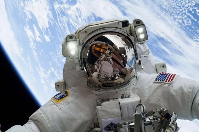 Astronaut Mike Hopkins, Expedition 38 Flight Engineer, is shown in this handout photo distributed today by NASA as he participates in the second of two spacewalks which took place on December 24, 2013. The scheduled spacewalks were designed to allow the crew to change out a faulty water pump on the exterior of the Earth-orbiting International Space Station. He was joined on both spacewalks by NASA astronaut Rick Mastracchio, whose image shows up in Hopkins' helmet visor. (Photo by NASA via Reuters)