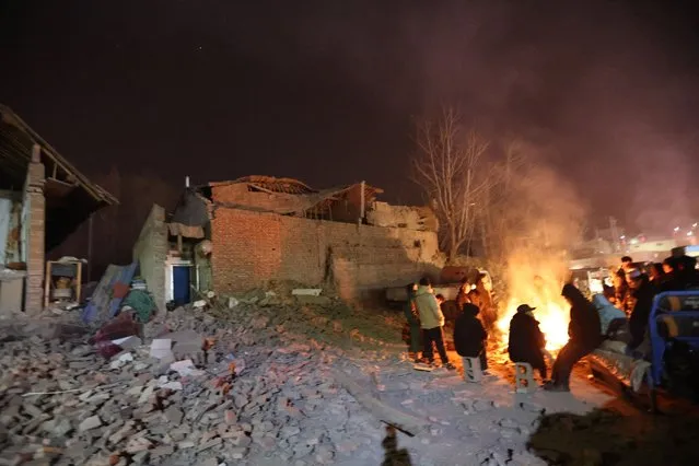 Residents keep warm around a fire in the early morning after an earthquake in Dahejia, Jishishan County, in northwest China's Gansu province on December 19, 2023. At least 111 people were killed when an earthquake collapsed buildings in northwest China, state media reported on December 19, as rescue workers raced to start digging through rubble. (Photo by AFP Photo/China Stringer Network)