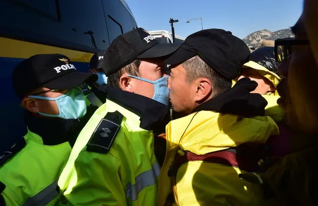 A relative (R) of the victims of South Korea's Sewol ferry disaster is in a nose-to-nose stand-off with a policeman (L) during an anti-government protest near the presidential residence in Seoul on April 17, 2015. Dozens of people continued their protests overnight after thousands of mourners rallied to mark the first anniversary of the disaster that claimed 304 lives. (Photo by Jung Yeon-Je/AFP Photo)
