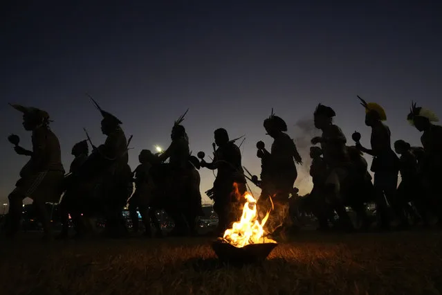 Indigenous men perform a ritual dance as Indigenous groups set up the “Luta pela Vida” or Struggle for Life camp, in Brasilia, Brazil, Monday, August 23, 2021. The groups arrive to the capital for a weeklong Struggle for Life mobilization to protests against a Supreme Court ruling that could undermine rights to their lands, and against President Jair Bolsonaro's government. (Photo by Eraldo Peres/AP Photo)