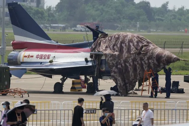 Ground crew cover a jet from the "August 1st" Aerobatic Team of the Chinese People's Liberation Army (PLA) Air Force after a performance during the 13th China International Aviation and Aerospace Exhibition, also known as Airshow China 2021, on Tuesday, September 28, 2021, in Zhuhai in southern China's Guangdong province. (Photo by Ng Han Guan/AP Photo)
