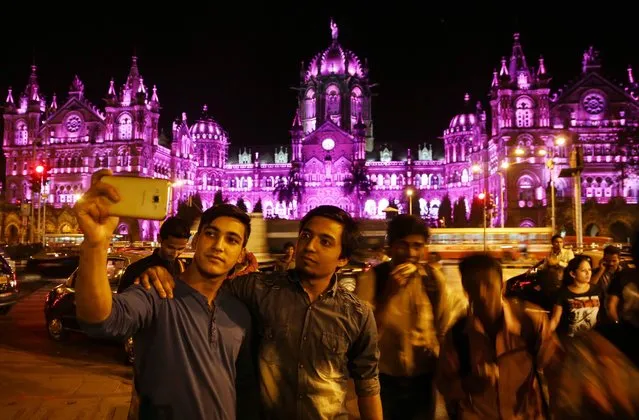Indian people takes selfies in front of the Chhatrapati Shivaji Terminus railway station, that's lit up in pink in support of International Women's Day, in Mumbai, India, 08 February 2016. (Photo by Divyakant Solanki/EPA)