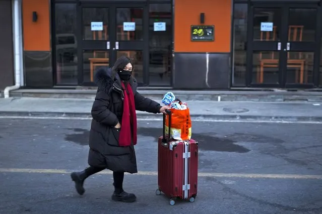 A woman with her luggage walks by a restaurant closed for the upcoming Lunar New Year as she leaves a village to catch her transport on the outskirt of Beijing, Tuesday, February 6, 2024. Widespread snowfall and freezing weather continued in central and eastern China disrupting transport and stranding travelers amid the annual Lunar New Year travel rush. (Photo by Andy Wong/AP Photo)