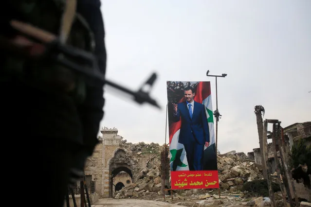 A Syrian army soldier stands guard as a poster depicting Syria's President Bashar al-Assad is seen in the background in the Old City of Aleppo, Syria January 31, 2017. (Photo by Ali Hashisho/Reuters)