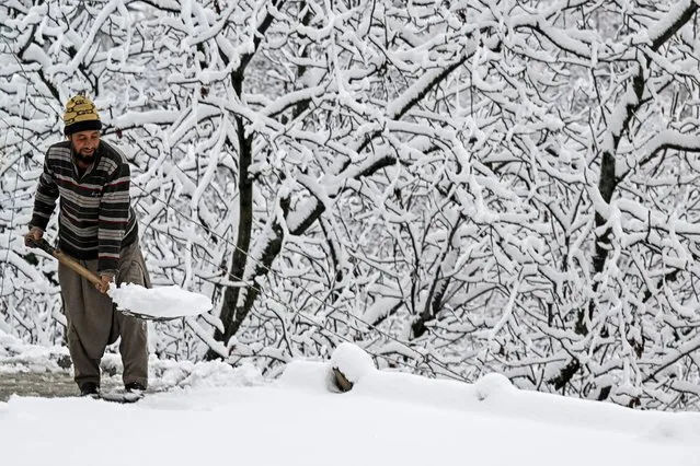 A man clears snow from the roof a house following the first snowfall of the winter on the outskirts of Srinagar on February 1, 2024. (Photo by Tauseef Mustafa/AFP Photo)