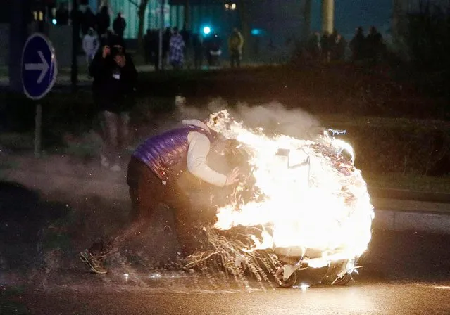 A man ignites a burning barricade as protesters clash with French riot police in Bobigny, a suburb of Paris, France, 11 February 2017, after attending a demonstration in support of Theo, a young man who was hospitalised for an emergency surgery after he was allegedly sodomized with a truncheon during a police check. (Photo by Yoan Valat/EPA)