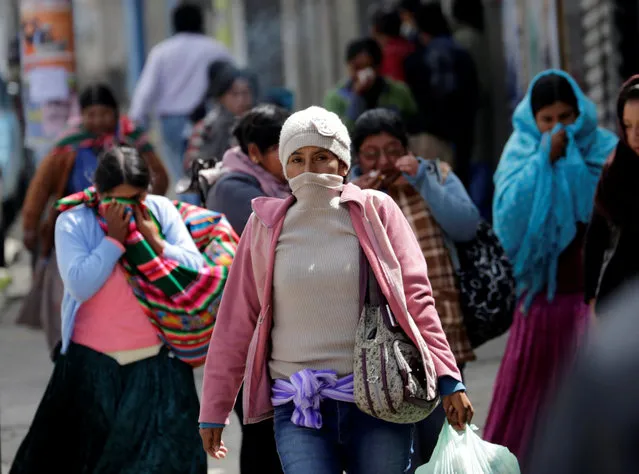 Women protect themselves from tear gas during clashes of coca growers from Yungas with riot policemen in La Paz, Bolivia, February 21, 2017. (Photo by David Mercado/Reuters)