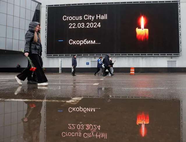 People walk to lay flowers at a makeshift memorial to the victims of a shooting attack at the Crocus City Hall concert venue in the Moscow Region, Russia, on March 23, 2024. (Photo by Yulia Morozova/Reuters)