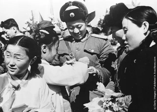 1958: Korean girls present a member of the Chinese People's Volunteer Army with a bouquet of flowers prior to the mass withdrawal of Chinese troops from North Korea