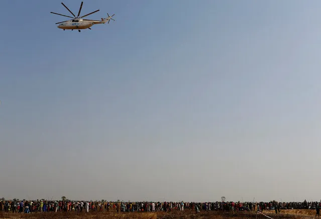 A United Nations World Food Programme (UN WFP) helicopter flies over a queue of people waiting to be registered prior to a food distribution in Thonyor, Leer county, South Sudan, February 25, 2017. (Photo by Siegfried Modola/Reuters)