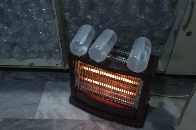 Bottles of saline are laid to warm up on top of an electric heater in Wazir Mohammad Akbar Khan National Hospital, in Kabul Afghanistan, Monday, December 5, 2021. (Photo by Petros Giannakouris/AP Photo)