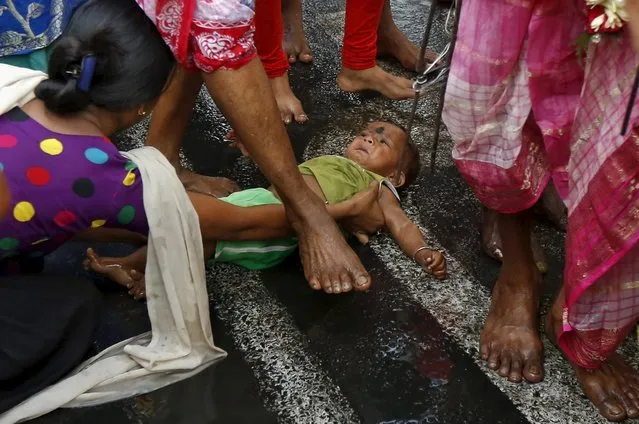 A Hindu holy man (not pictured) steps over an infant after touching him with his foot as part of a ritual to bless him during a religious procession to mark the Gajan festival in Kolkata, India, April 12, 2016. REUTERS/Rupak De Chowdhuri