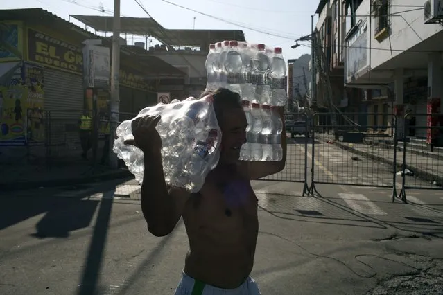 A man carries bottled water from a supermarket that collapsed due to a 7.8 magnitude earthquake, in the business district of Manta, Ecuador, Tuesday, April 19, 2016. (Photo by Rodrigo Abd/AP Photo)