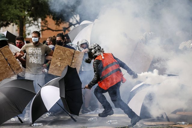 A pro-Palestinian protester returns a tear-gas canister toward police after it tumbled into a congregation of protesters at MLK Plaza at the University of South Florida, Tuesday, April 30, 2024, in Tampa, Fla. (Photo by Douglas R. Clifford/Tampa Bay Times via AP Photo)
